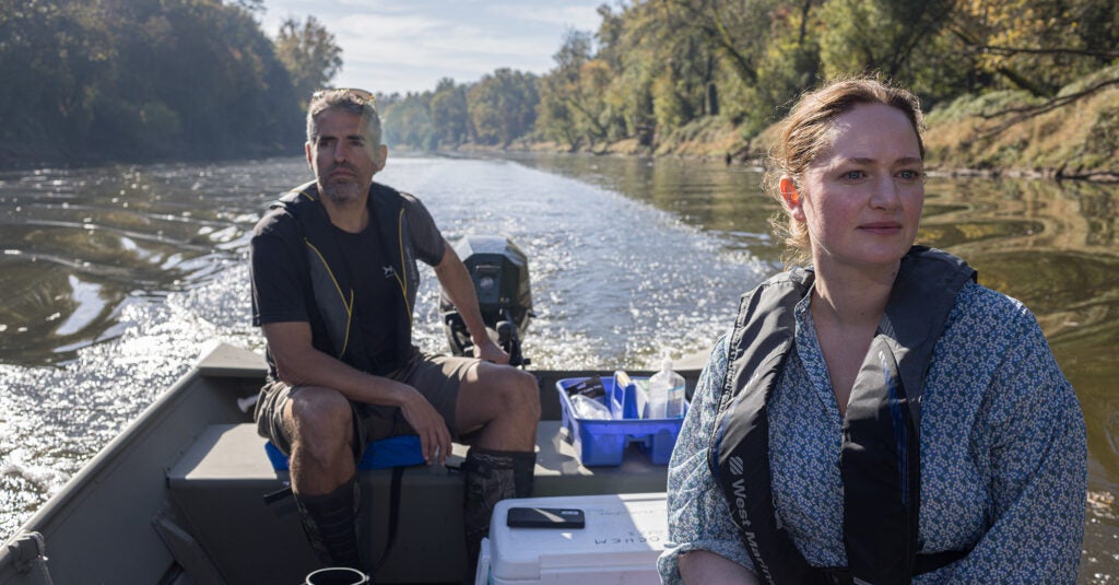 Cape Fear Riverkeeper Kemp Burdette pilots a small boat on the Cape Fear River, with Earthjustice attorney Alexis Andiman seated in the boat. They are collecting water samples in the Cape Fear River near the Smithfield slaughterhouse in Tar Heel, North Carolina, on October 2023.
