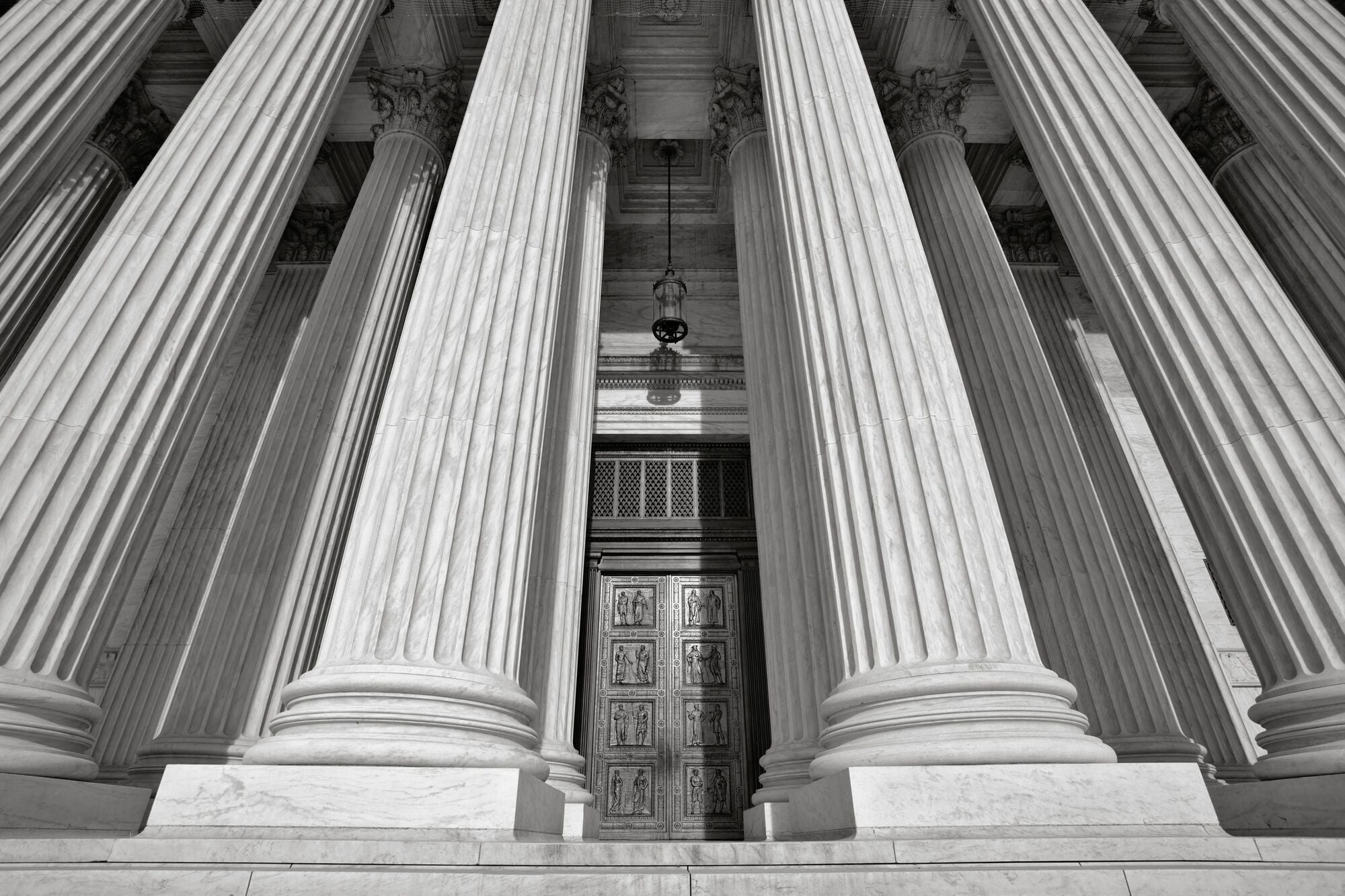 An upward view of the U.S. Supreme Court building near the top of the front steps.
